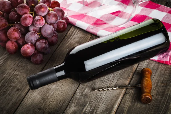 Garrafa de vinho saca-rolhas amd uvas na mesa de madeira — Fotografia de Stock