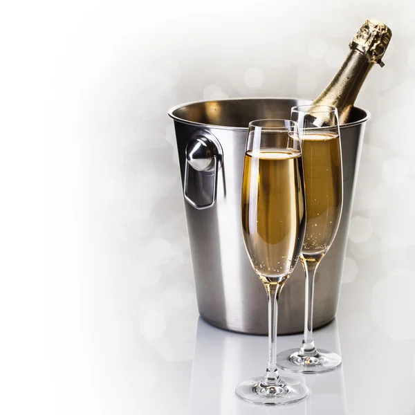 Champagneflaska i hink med glas champagne — Stockfoto