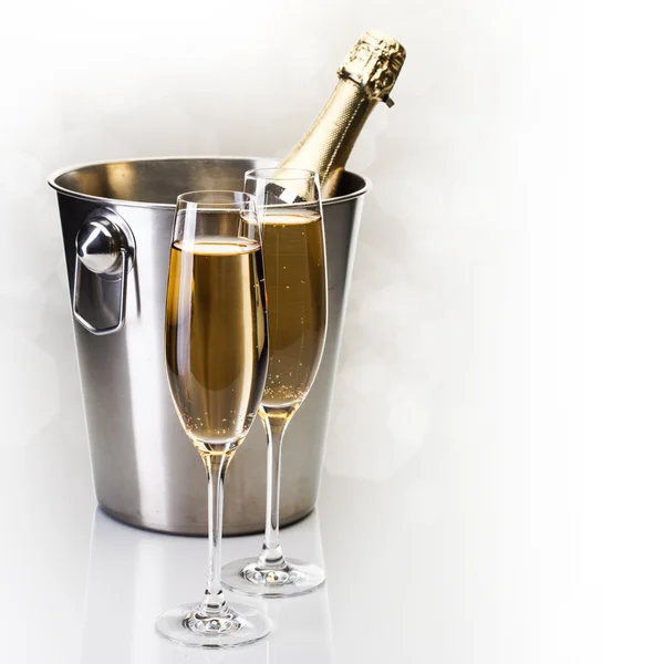 Champagneflaska i hink med glas champagne — Stockfoto