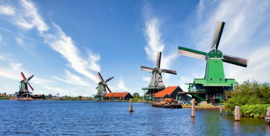 ZAANSE SCHANS, NETHERLANDS - CRCA AĞUSTOS 2020: Hollanda yel değirmeni Amsterdam yakınlarında, mavi gökyüzü ve nehir suyuyla.