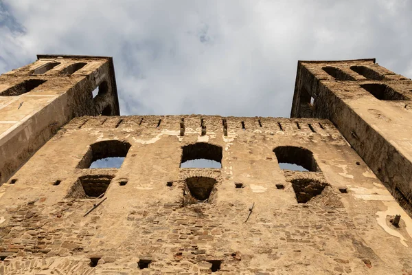 Ortaçağ taş kemerleri ve ikiz kuleleri olan antik bir kale duvarının düşük açılı görüntüsü, bulutlu bir gökyüzünün altında tarihi mimari, doku ve kültürel mirası gösteriyor..
