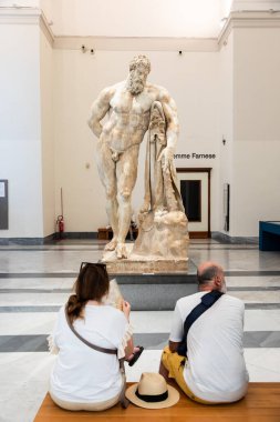 Turistler, Napoli Arkeoloji Müzesi 'ndeki devasa Farnese Herkül heykelini kültürel turizm ve klasik sanatın takdir edilmesini ön plana çıkararak gözlemlediler..