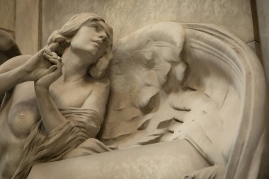 Zarif kanatları ve narin ifadesini gösteren mermer bir melek heykelinin yakın çekimi güzelliği, maneviyatı ve sanatsal zanaatı simgeliyor..