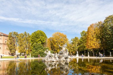 TURIN, ITALY ECTOBER 2025 Çeşme heykelleri sonbaharda Giardini Reali 'deki bir gölete yansıdı, renkli ağaçlar ve Torino' nun tarihi kraliyet bahçelerinde yürüyen ziyaretçiler.