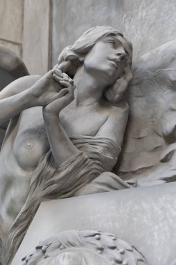 Zarif kanatları ve narin ifadesini gösteren mermer bir melek heykelinin yakın çekimi güzelliği, maneviyatı ve sanatsal zanaatı simgeliyor..