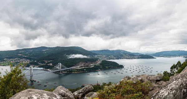 Ria de Vigo nehrinin bulutlu bir yaz öğleden sonrasında Redondela 'dan havadan görünüşü, sol taraftaki Rande Köprüsü ile birlikte..