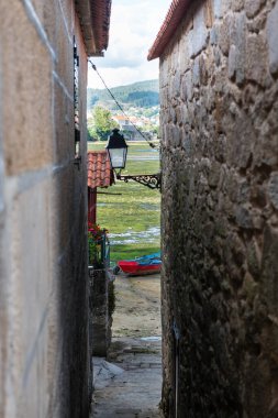 Pontevedra Ria, İspanya 'nın Ponteveda kentindeki iyi korunmuş Combarro köyünde dar bir taş sokaktan görülüyor..