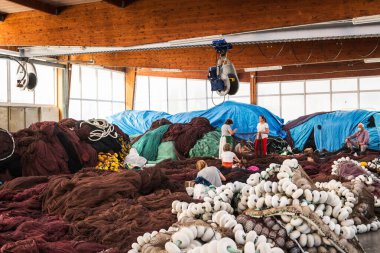 SANXENXO, İspanya - 20 Mayıs 2021: Portonovo balıkçı iskelesindeki balık ağlarını onaran Galiçyalı ağ tamircileri, İspanya.