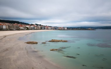 İspanya, Galiçya 'daki Rias Baixas' ta bulutlu bir bahar gününün sonunda Sanxenxo ve Silgar sahillerinin panorama manzarası. Uzun pozlama.