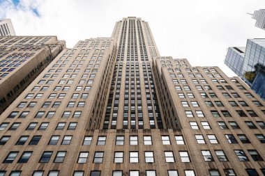 Manhattan, New York 'ta yüksek bir gökdelenin alçak açılı görüntüsü klasik Art Deco mimari tarzını sergiliyor. Dramatik perspektif, bu tarihi gökdelenin dikey çizgilerini, tekrarlayan pencere modellerini ve muazzam ölçeğini vurgular.,