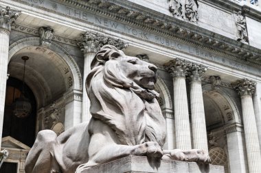 New York Halk Kütüphanesi 'nin ön girişini çevreleyen aslan heykelinin açılı görüntüsü, arka planda çözünmüş ön cephe.