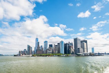 Aşağı Manhattan, New York 'taki Battery Park' ı çevreleyen gökdelenlerin panoramik görüntüsü. Dünya Ticaret Merkezi, Hudson Nehri boyunca ikonik bir siluet oluşturan modern cam kuleler ve tarihi binalar arasında belirgin bir şekilde yükselir. Bir ferr.