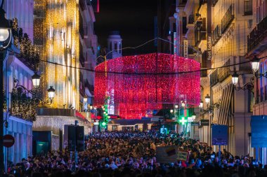 MADRID, SPAIN - 4 HAZİRAN 2026: Şehrin en işlek yaya alışveriş caddelerinden biri olan Madrid 'in merkezindeki Calle Preciados' u dolduran bir insan denizi, şenlikli Noel ışıkları akşam güneşlenirken.