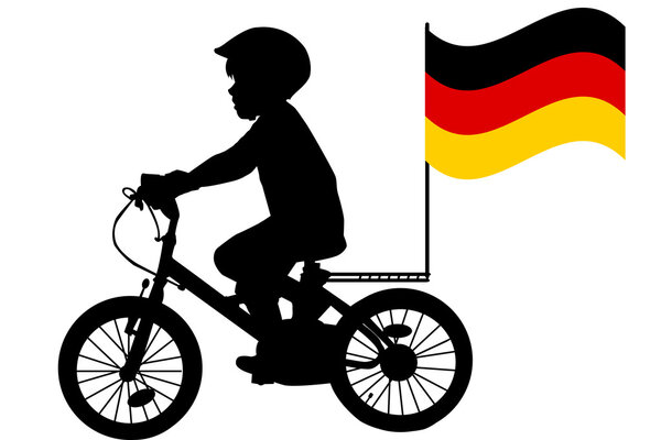 A kid rides a bicycle with German flag