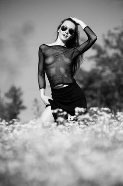 Çiçekli bir tarlada şeffaf maviler içinde poz veren güzel, seksi sarışın kız.