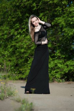 Siyah bluzlu, yeşil yapraklı güzel sarışın kız.