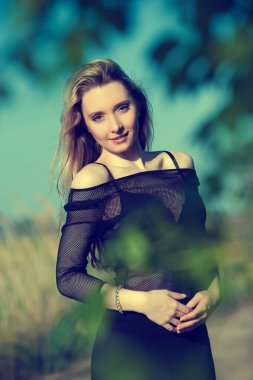 Siyah bluzlu, yeşil yapraklı güzel sarışın kız.