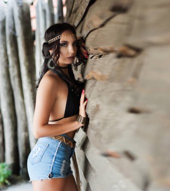 Kovboy tarzı giyinmiş güzel, seksi esmer kız vahşi batı tarzı poz veriyor.