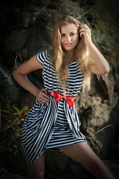 Sexy girl in striped dress on the rocks — Stock Photo, Image