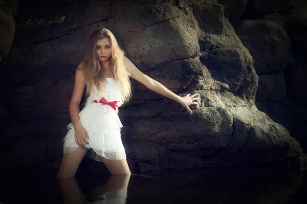 Blonde girl in the water leaning on rock — Stock Photo, Image