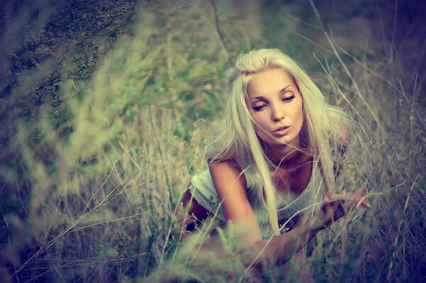 Beautiful sexy blonde girl posing in a high grass