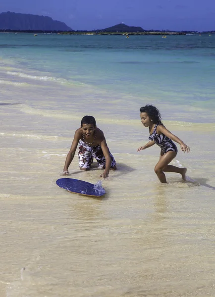 Boy teaching sister to skim board — Stock Photo, Image