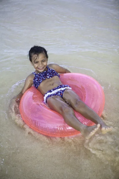 Kleines Mädchen schwimmt auf einem rosa Floß — Stockfoto