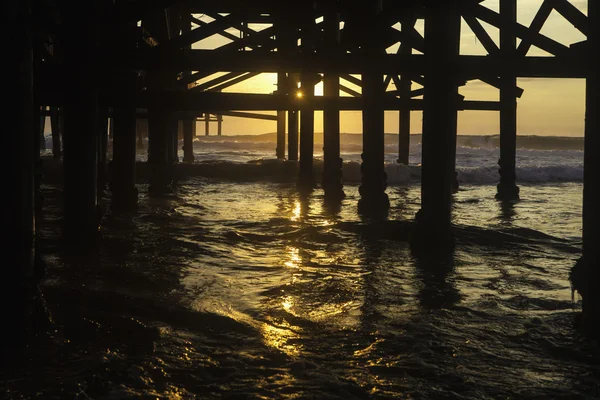 Puesta de sol bajo un muelle — Foto de Stock