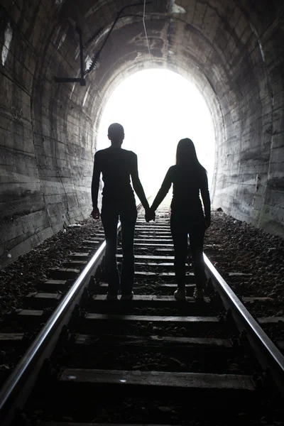 Casal caminhando juntos através de um túnel ferroviário — Fotografia de Stock