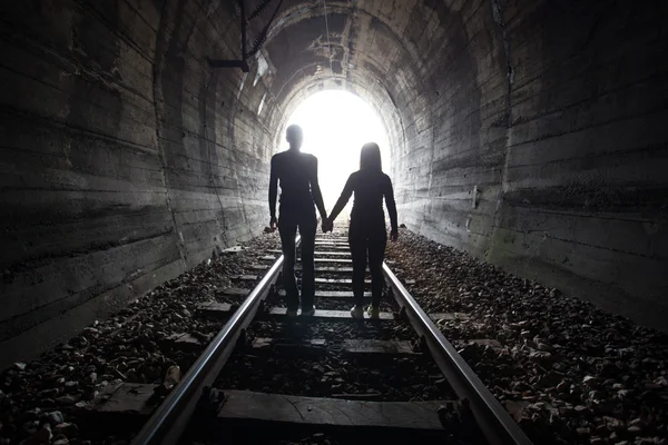 Casal caminhando juntos através de um túnel ferroviário — Fotografia de Stock