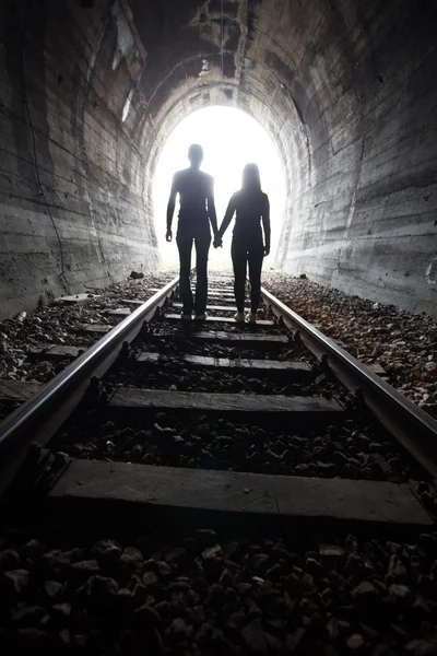 Casal caminhando juntos através de um túnel ferroviário — Fotografia de Stock