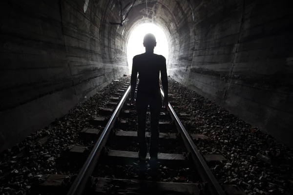 Homem em um túnel olhando para a luz — Fotografia de Stock