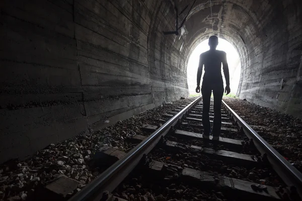 Man in a tunnel looking towards the light — Stock Photo, Image