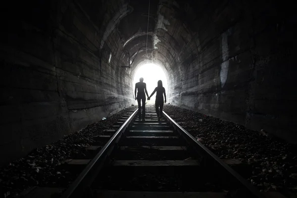 Casal caminhando juntos através de um túnel ferroviário — Fotografia de Stock