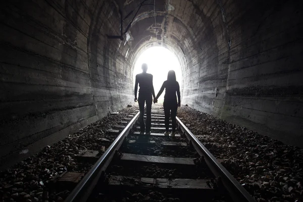 Casal caminhando juntos através de um túnel ferroviário — Fotografia de Stock