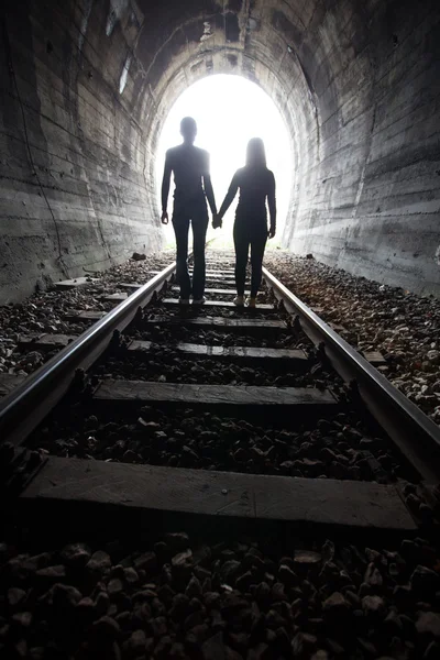 Casal caminhando juntos através de um túnel ferroviário — Fotografia de Stock