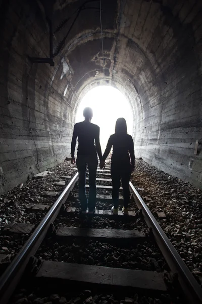 Casal caminhando juntos através de um túnel ferroviário — Fotografia de Stock