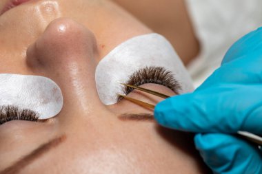 Kirpiklerin iyileştirme prosedürü Cımbızla uzatılmış uzun kirpikli kadın gözleri