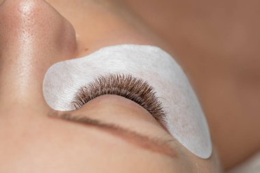 Güzellik tedaviden sonra göz bandıyla uzun kirpikli bir kadın gözü.