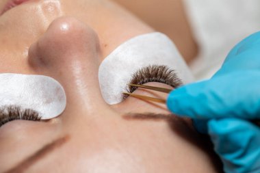 Kirpiklerin iyileştirme prosedürü Cımbızla uzatılmış uzun kirpikli kadın gözleri