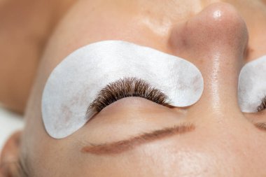 Güzellik tedaviden sonra göz bandıyla uzun kirpikli bir kadın gözü.