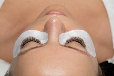 Uzun kirpikli, uzun kirpikli ve göz bantlı bir kadın. Sahte Kırbaçlar Güzellik Tedavisi