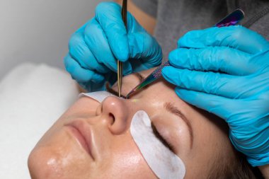 Kirpiklerin iyileştirme prosedürü Cımbızla uzatılmış uzun kirpikli kadın gözleri