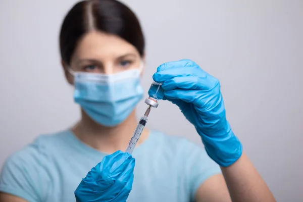 Doctor Scientist in protective gloves and mask holding glass vial with injection liquid. Vaccination against influenza and coronavirus. Stock photo