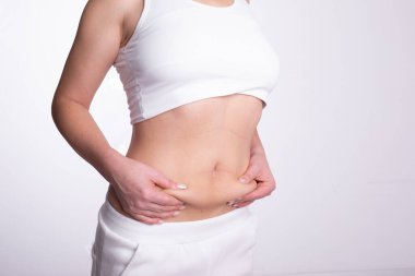 Göbekteki yağ oranını ölçmek için çimdik testi uygulayan bir kadın.