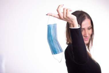 Mutlu kadın koruyucu maskeyi çıkartıyor parmağında tutuyor, hayattan zevk alıyor, Covid-19 salgınından sonra temiz hava alıyor, kendini izole ediyor. Karantina stok fotoğrafı üzerinde.