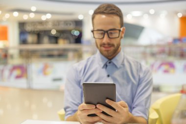 Genç işadamı oturma restoranda ve kullanım mobil de tablo