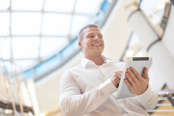 Lachende zakenman met tablet pc in de moderne zakenwereld buil — Stockfoto