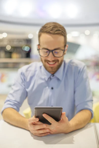 Junger Geschäftsmann sitzt auf einem Tisch in restoran und verwenden mobile de — Stockfoto