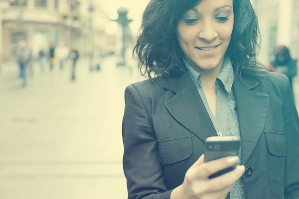 Femme avec téléphone portable marchant dans la rue — Photo